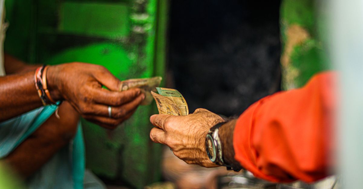 A close-up shot of two people exchanging currency in an outdoor market setting.